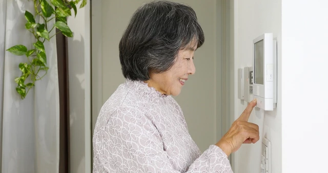 インターフォンに応答するシニア女性
