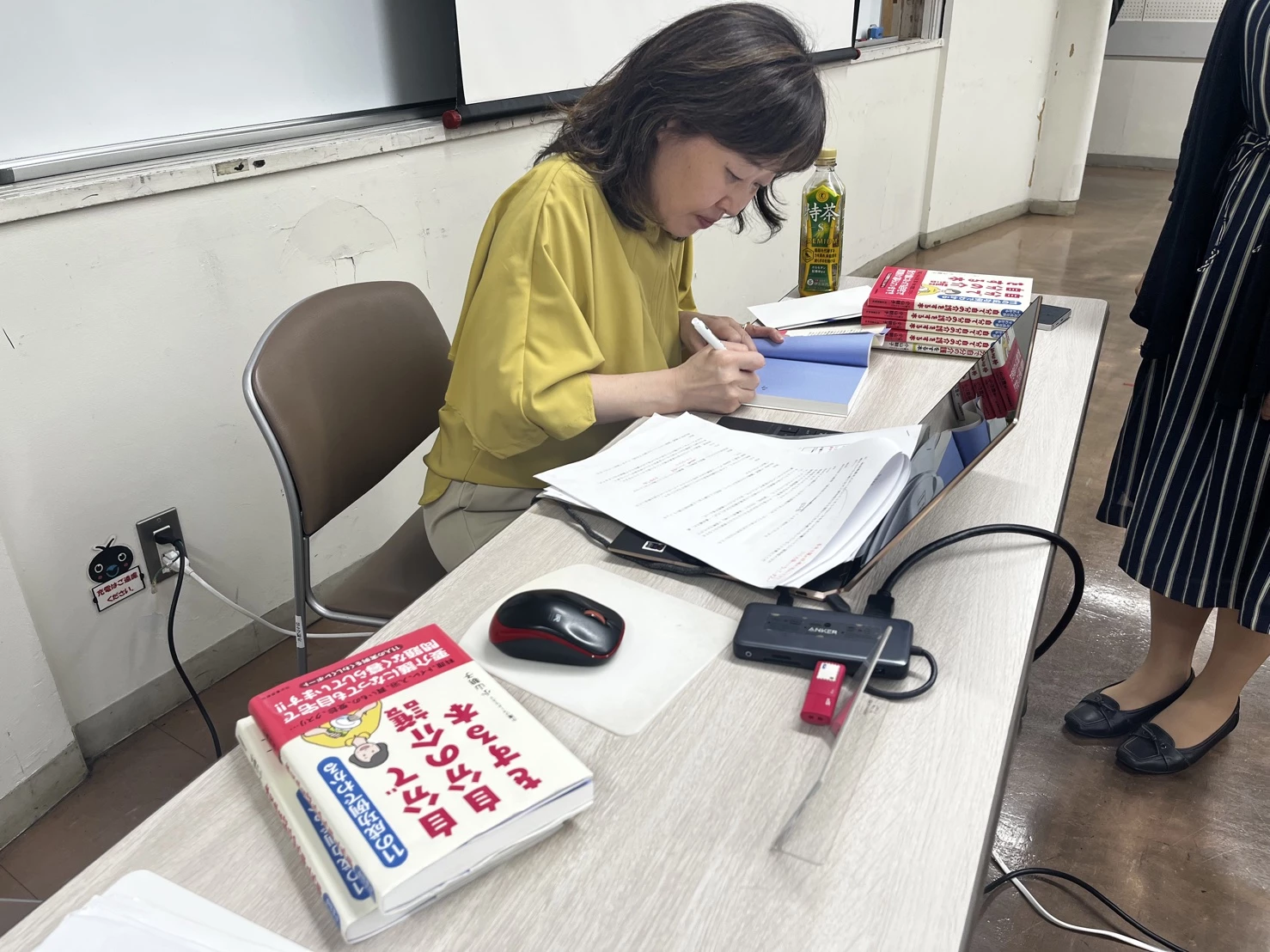 著書にサインをしている小山さん