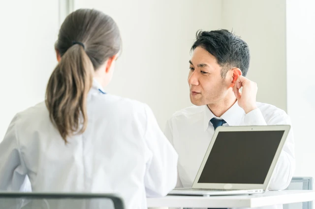 pixta_118738717_S.jpg 補聴器を試す男性