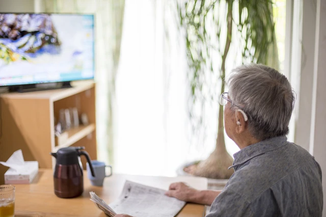 pixta_94976890_S.jpg 補聴器をつけてテレビを見るシニア男性