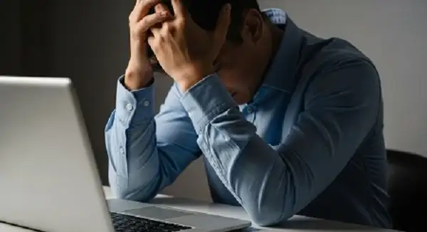 man-holds-head-despair-front-laptop-overwhelmed-stressed.jpg 疲れた状態の男性